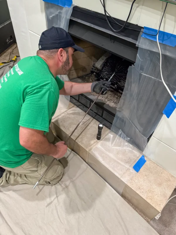 Technician cleaning chimney with brush tool